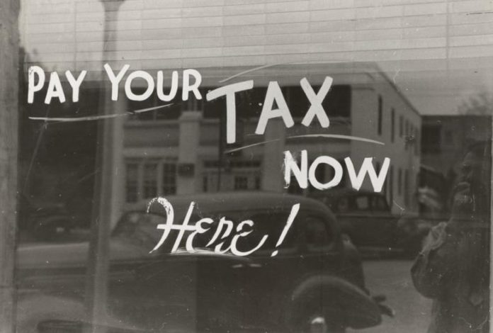 Text auf Glas:'Pay your Tax now here!'